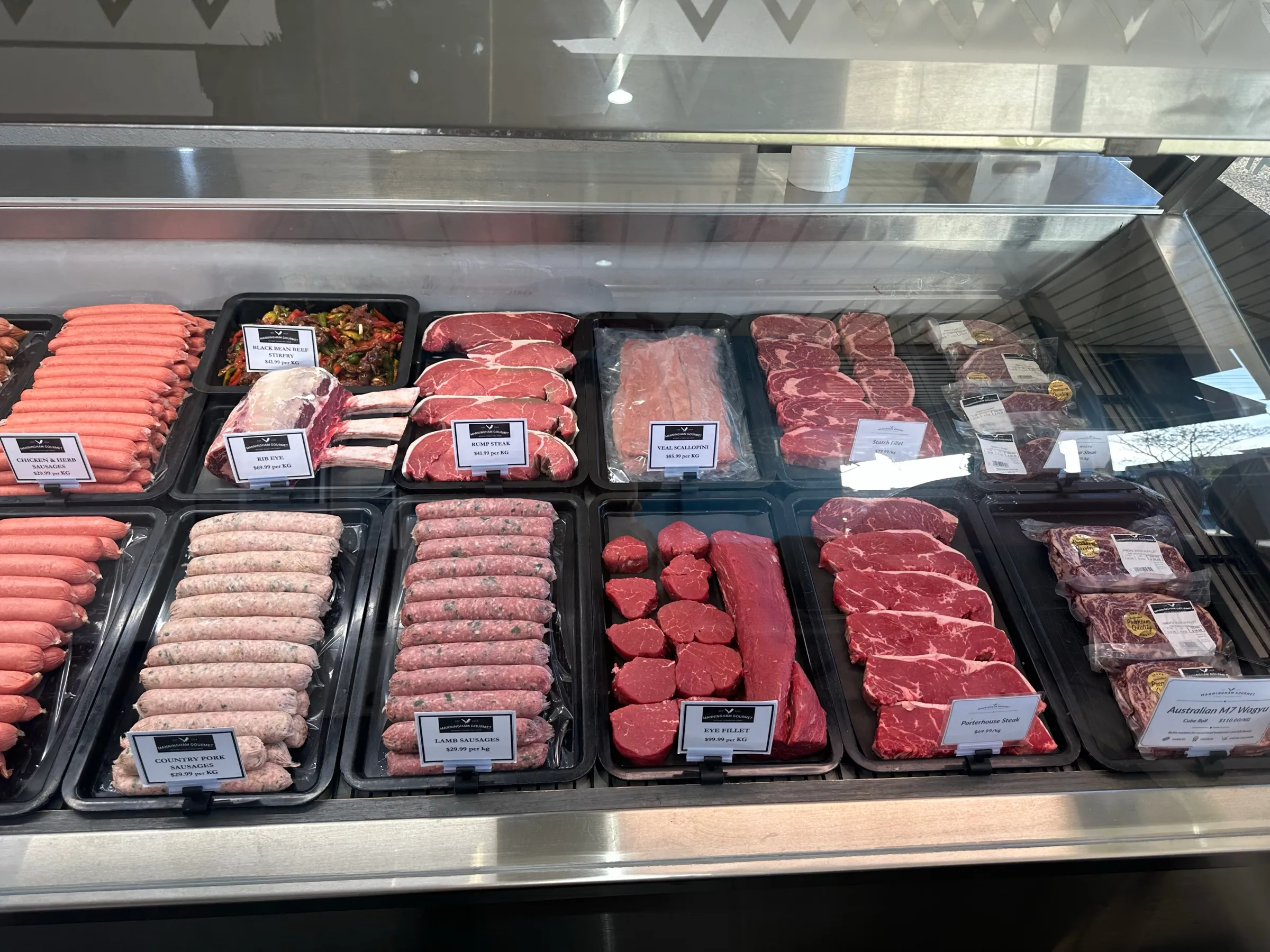 The meat cabinet at Manningham Gourmet, full of sausages, steaks and trays
